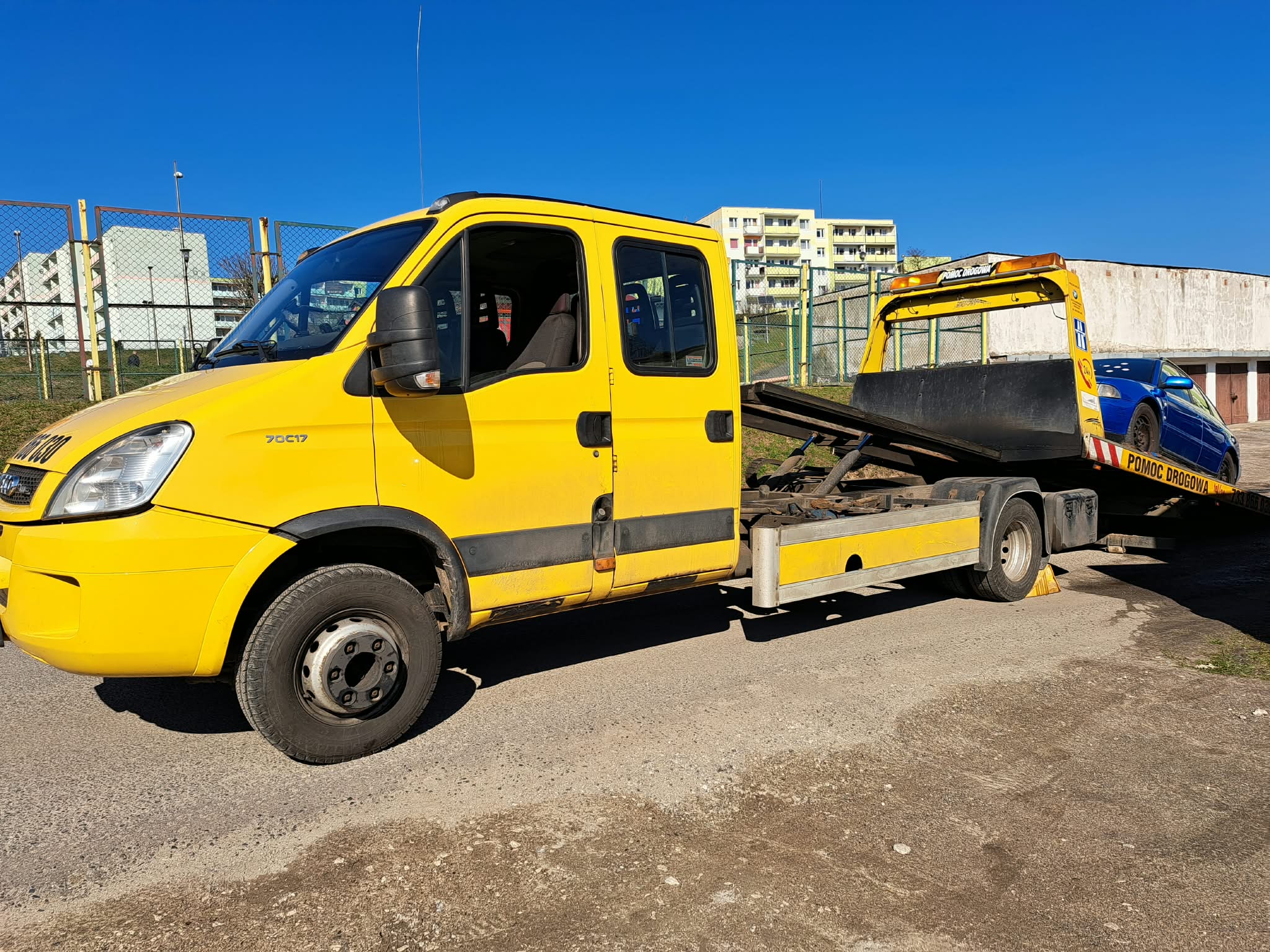 Żółta laweta firmy przygotowana do transportu samochodu
